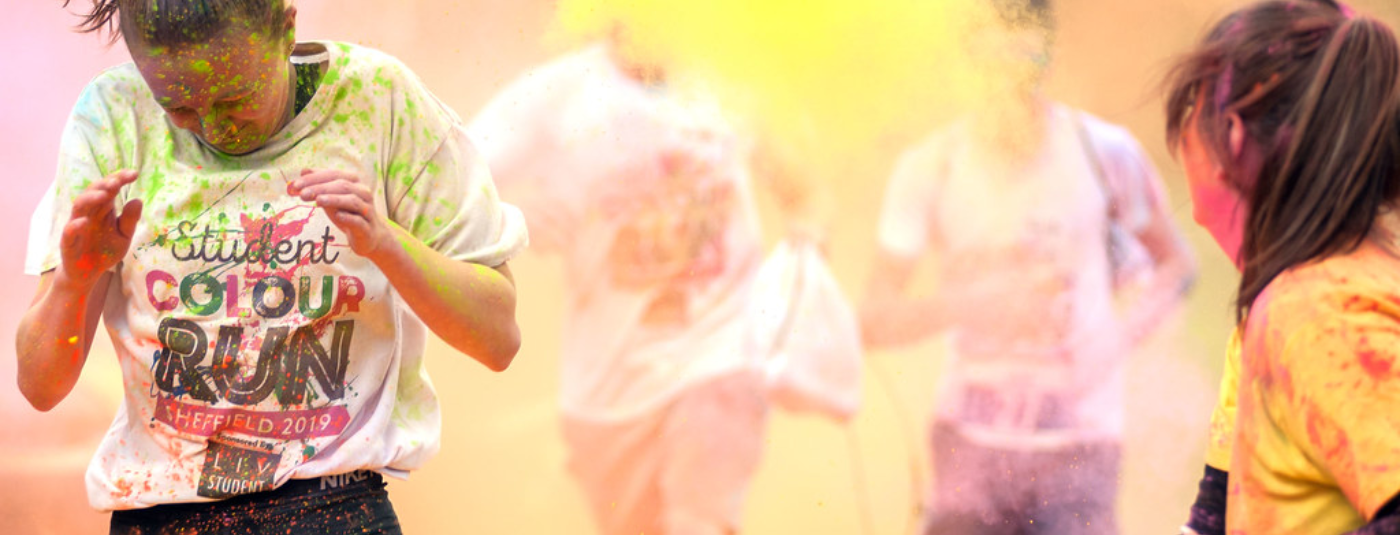 colour powder being thrown at a woman completing a colour run