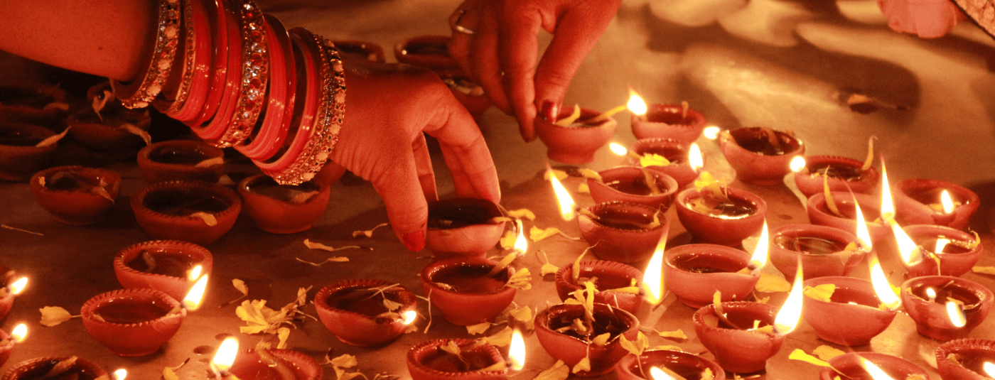 A person lighting oil lamps for Diwali celebrations